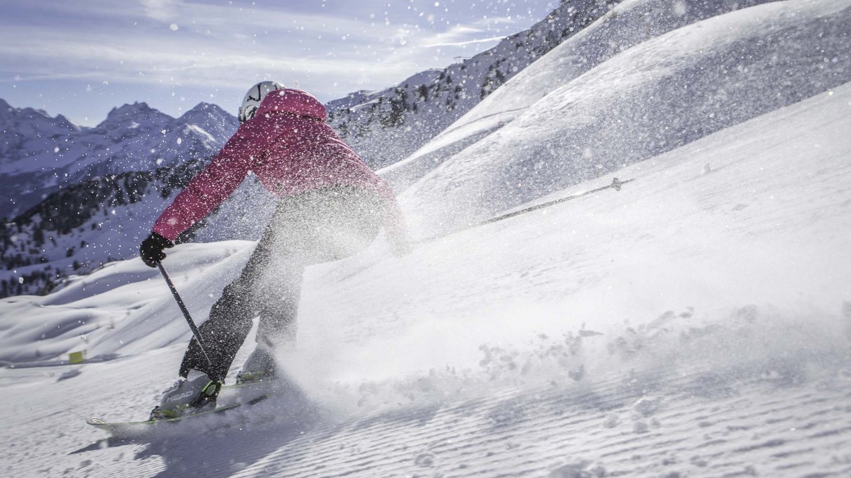 Deine Unterkunft im Pustertal: oh, wow! Skifahrer mit rosa Jacke fährt auf frischem Schnee im Gebirge