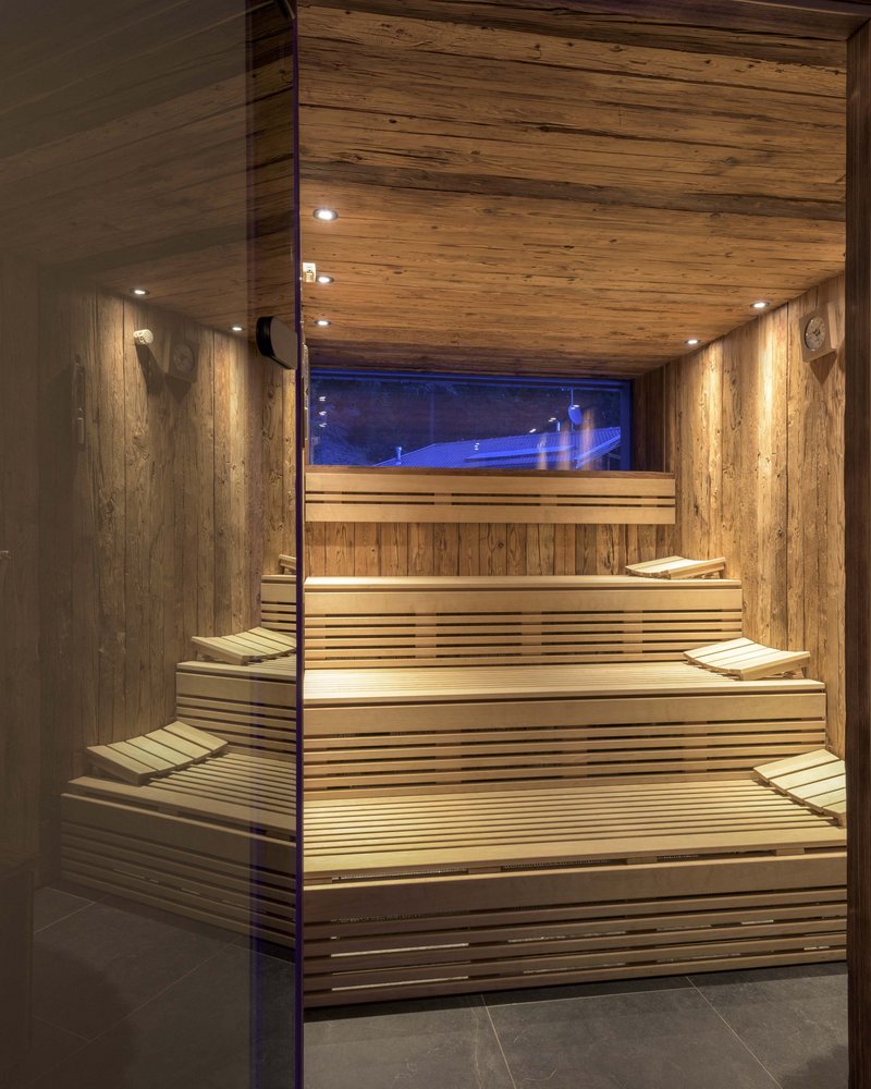 Dein Wellnesshotel am Kronplatz: Olangerhof Innenansicht einer modernen Holzsauna mit gestuften Bänken und Kissen