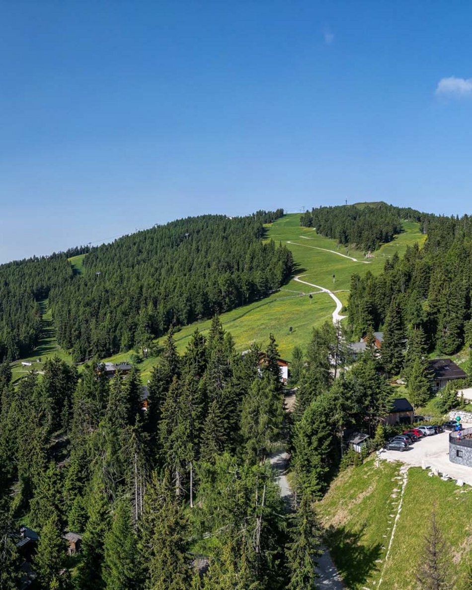 Dein Hotel im Pustertal: Olangerhof Modernes Hotel inmitten von Bäumen und Bergen unter klarem blauem Himmel