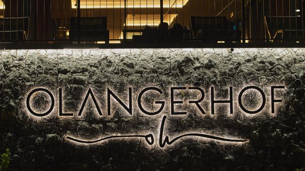 A Valdaora: l’hotel da “oh” Insegna luminosa OLANGERHOF su muro in pietra di notte