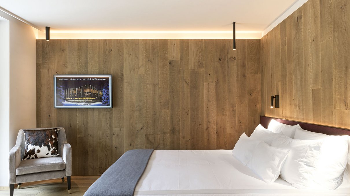 Deine Unterkunft im Pustertal: oh, wow! Modernes Schlafzimmer mit Holzwänden, weißem Bett und grauem Sessel