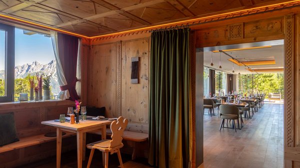 Dein Hotel in Olang: Willkommen im Olangerhof! Esszimmer aus Holz mit Bergblick und gedecktem Tisch