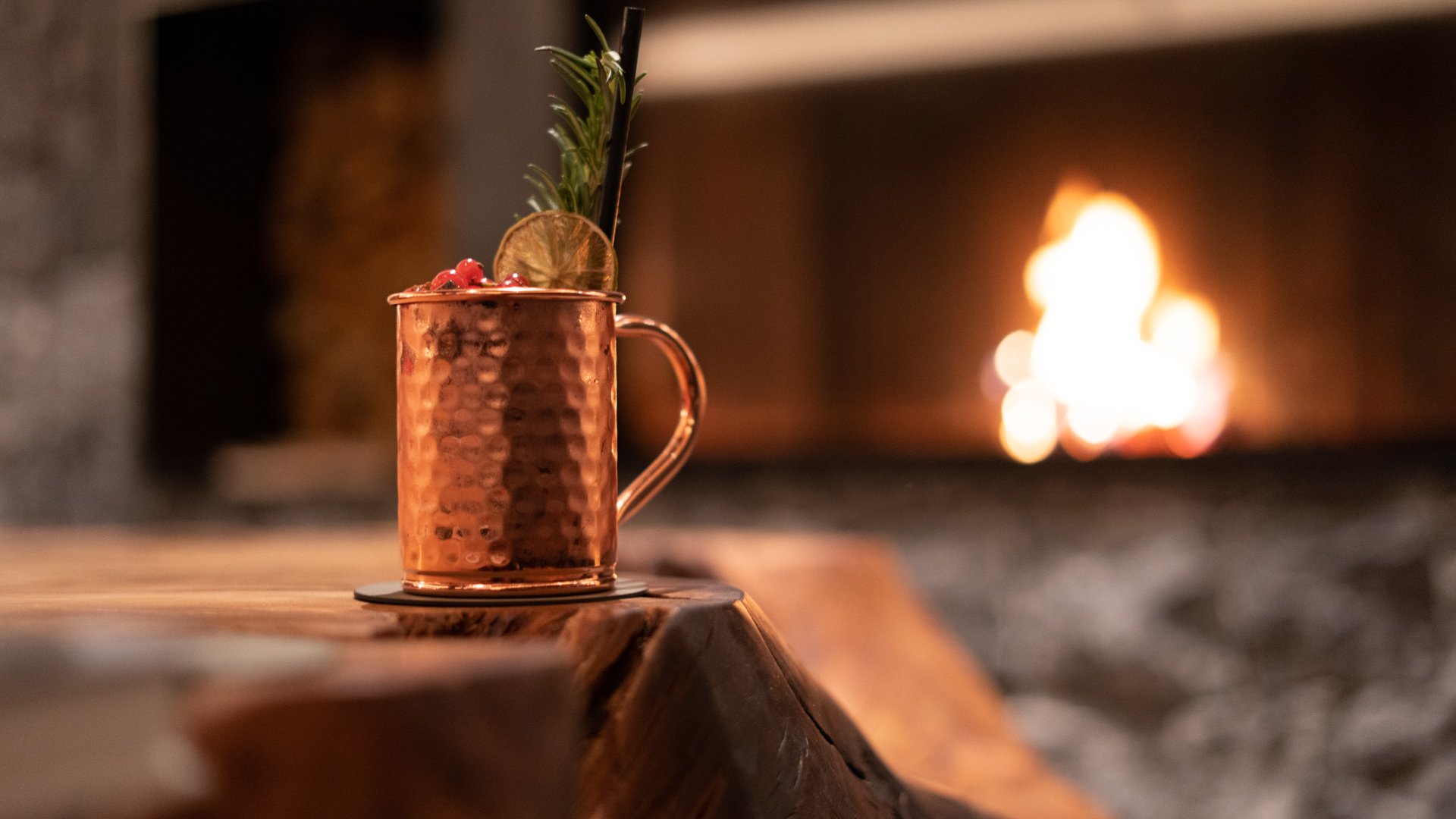 Hotel near Plan de Corones/Kronplatz: more flavour! Cocktail in copper mug with garnish by a lit fireplace