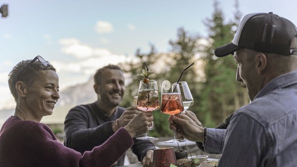 Dein Hotel in Olang: Willkommen im Olangerhof! Drei Freunde stoßen mit Cocktails an einem sonnigen Tag im Freien an