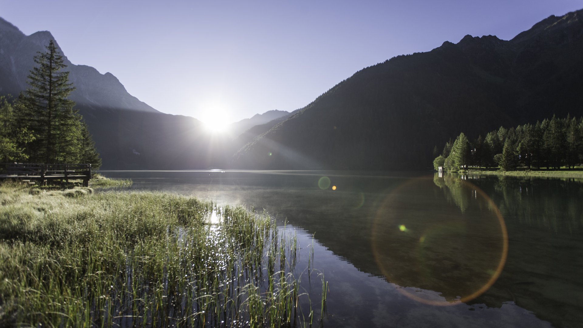 Olang: Wandern, Kunst und Kultur See umgeben von Bergen bei Sonnenuntergang mit Spiegelungen im ruhigen Wasser