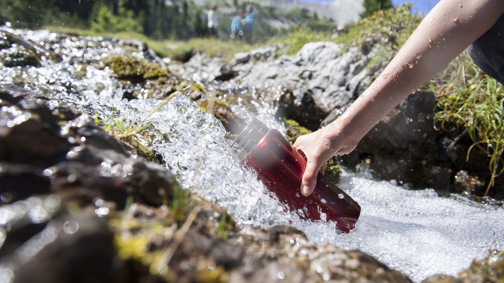 Escursioni a Valdaora nei pressi dell’Olangerhof Persona che riempie una borraccia con acqua di sorgente in montagna