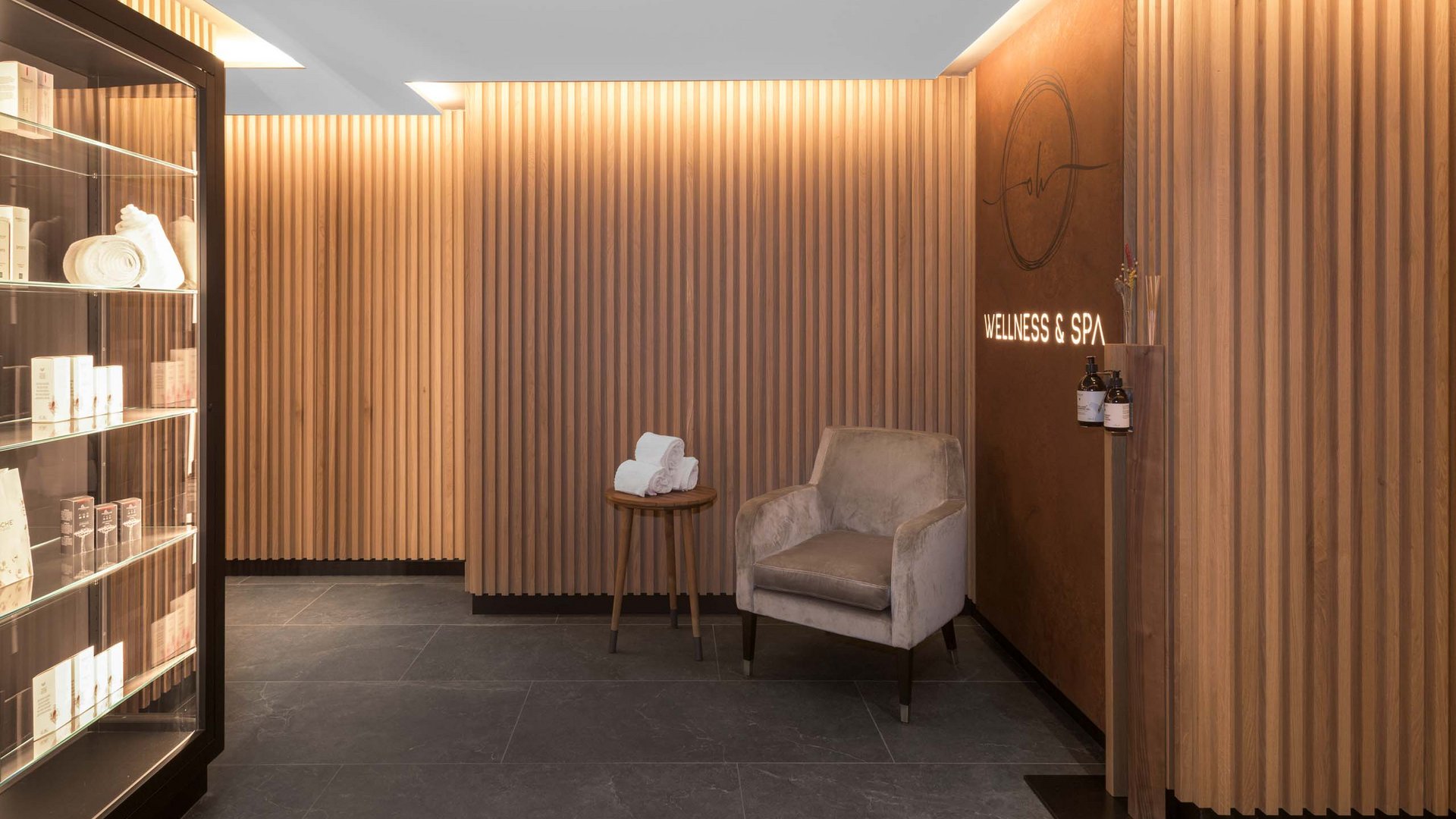 Dein Wellnesshotel am Kronplatz: Olangerhof Eleganter Spa-Eingang mit Sessel, Beistelltisch und Produktregal