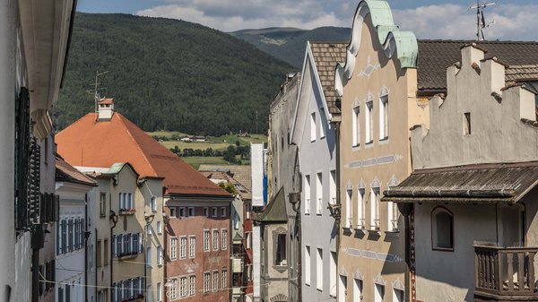 Olang: Wandern, Kunst und Kultur Bunte Häuser mit grünen Hügeln im Hintergrund an einem sonnigen Tag