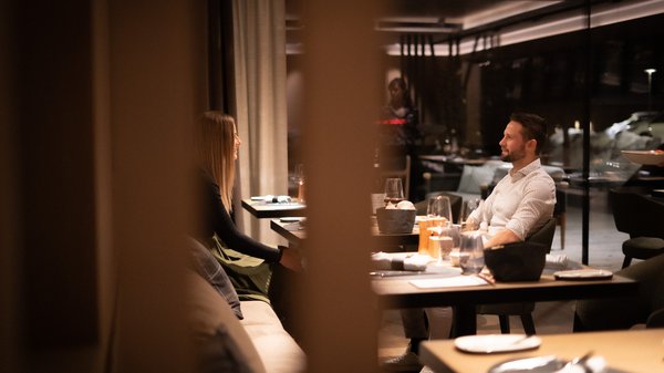 Dein Hotel in Olang: Willkommen im Olangerhof! Paar beim Abendessen in einem schicken Restaurant mit intimer Atmosphäre.