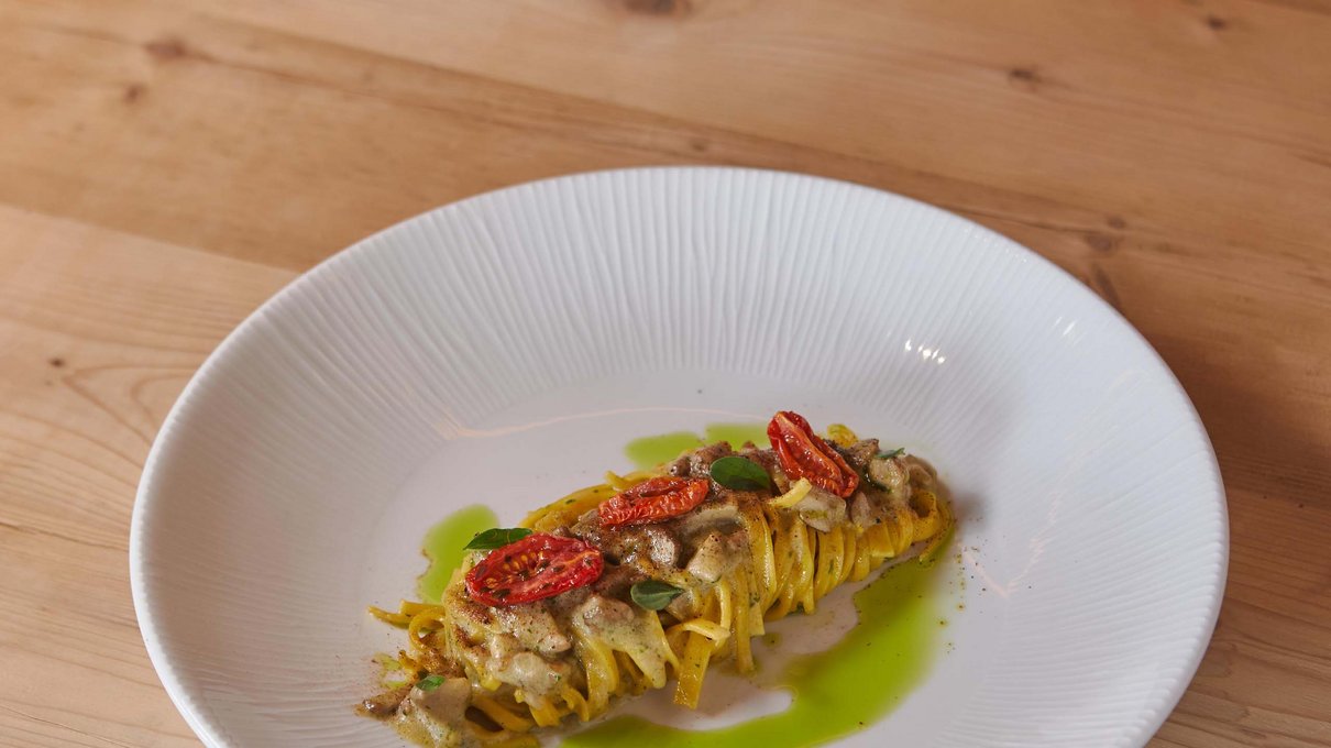 Deine Unterkunft im Pustertal: oh, wow! Pasta mit Kirschtomaten und grüner Soße auf weißem Teller