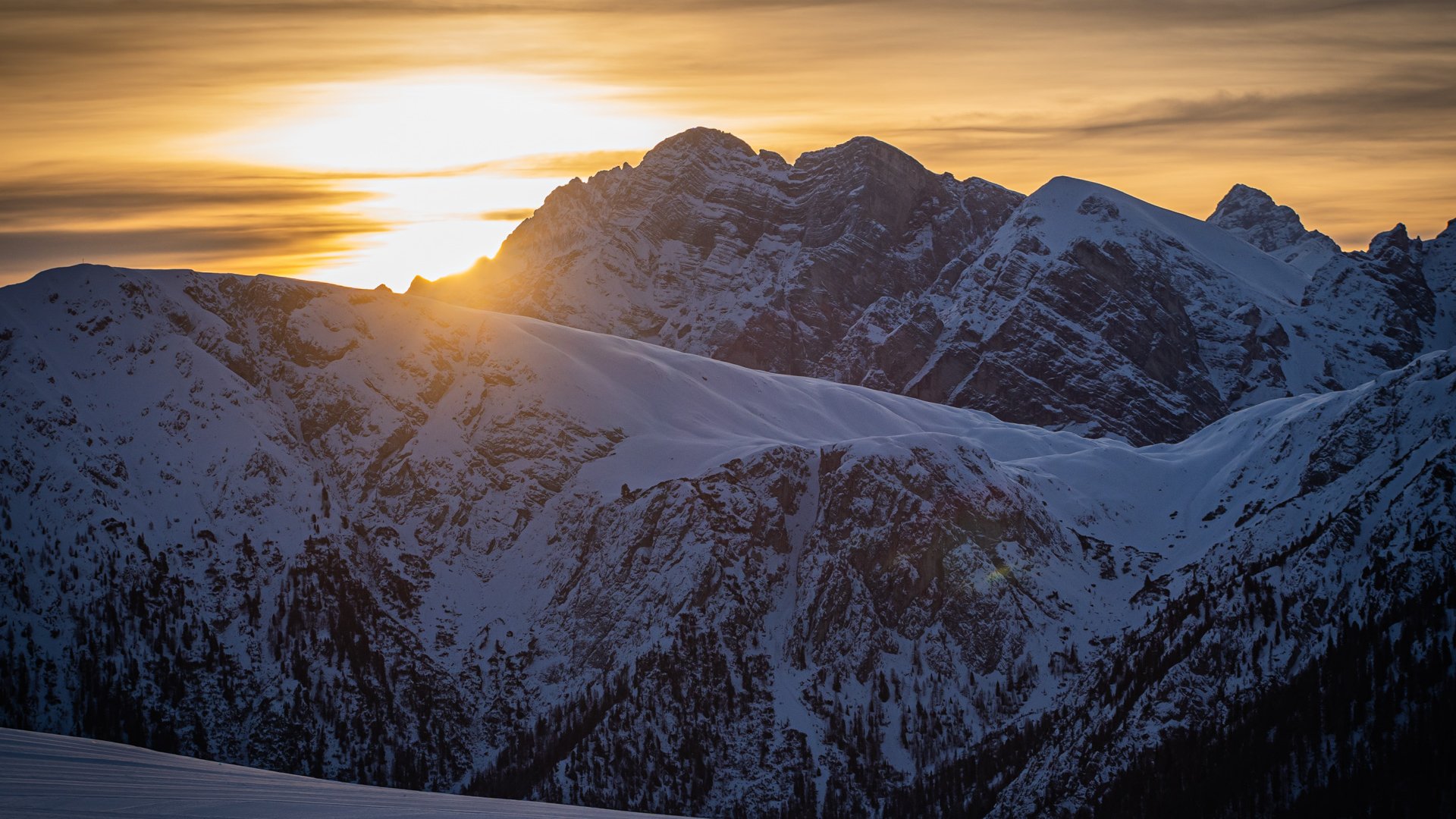 Olang in Südtirol: Wanderungen Sonnenuntergang über schneebedeckten Bergen mit orange-violettem Himmel