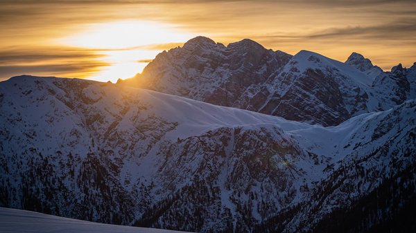 Dein Hotel in Olang: Willkommen im Olangerhof! Sonnenuntergang über schneebedeckten Bergen mit orange-violettem Himmel
