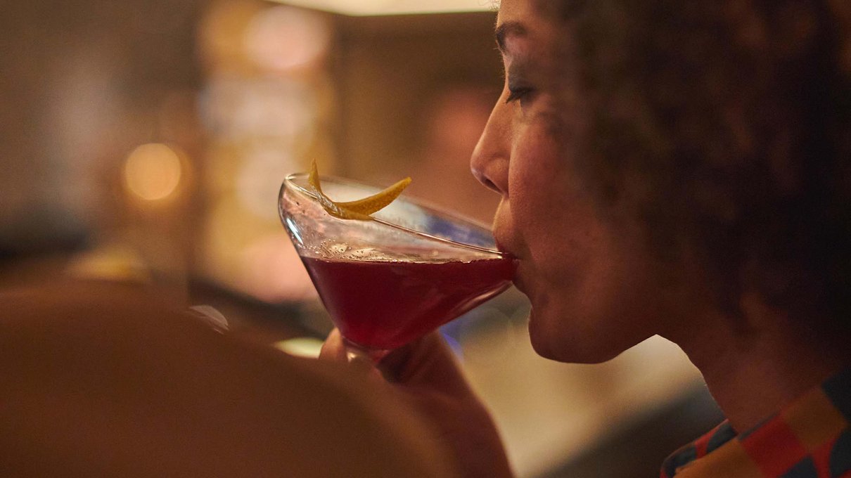 Deine Unterkunft im Pustertal: oh, wow! Frau trinkt roten Cocktail in einer Bar mit gedämpftem Licht