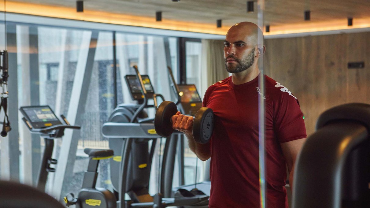 Deine Unterkunft im Pustertal: oh, wow! Mann trainiert mit Kurzhanteln in einem modernen Fitnessstudio
