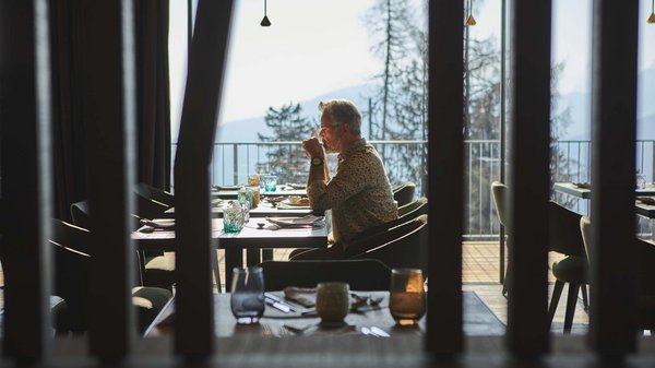 Hotels an der Piste in Südtirol mit Halbpension Mann trinkt Kaffee in einem Restaurant mit Bergblick