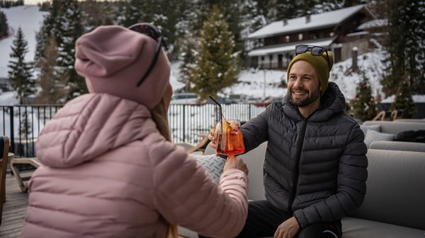 Dein Hotel in Olang: Willkommen im Olangerhof! Paar stößt mit Getränken in schneebedeckter Outdoor-Umgebung an