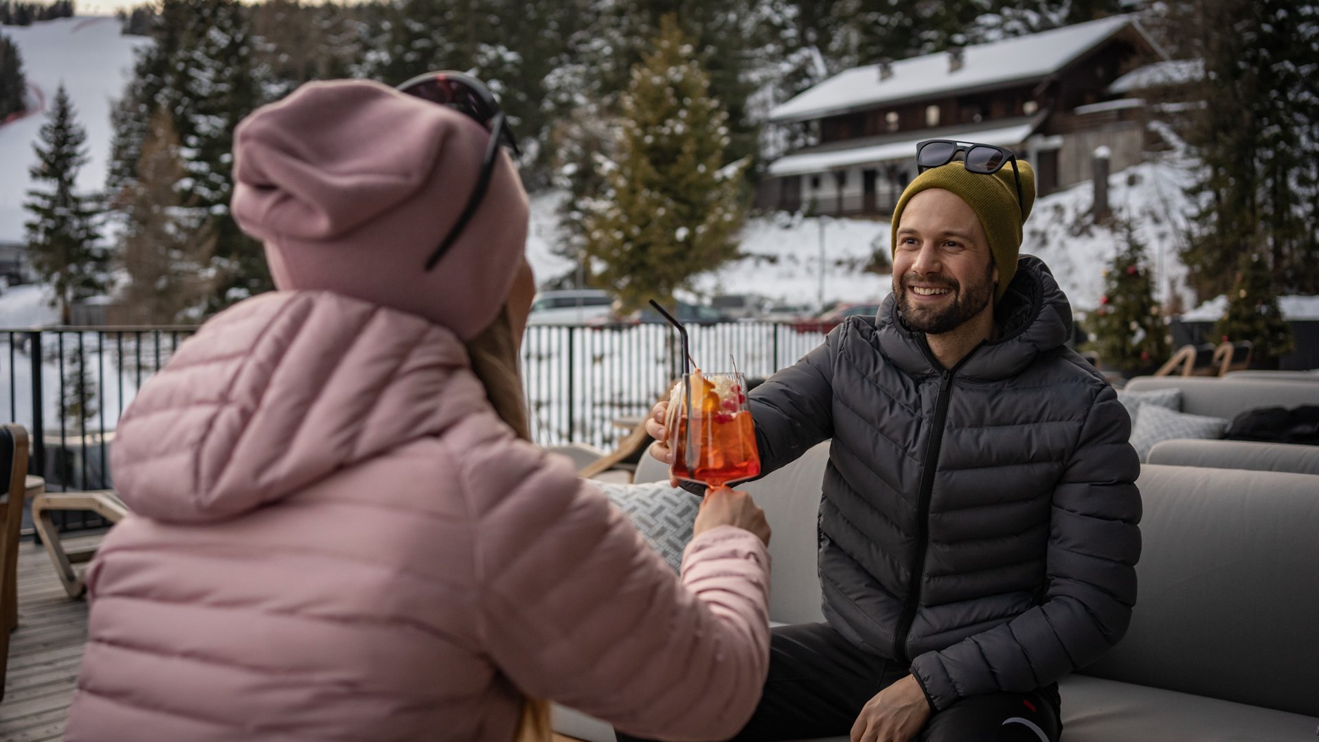 Hotels in Olang gesucht? Paar stößt mit Getränken in schneebedeckter Outdoor-Umgebung an