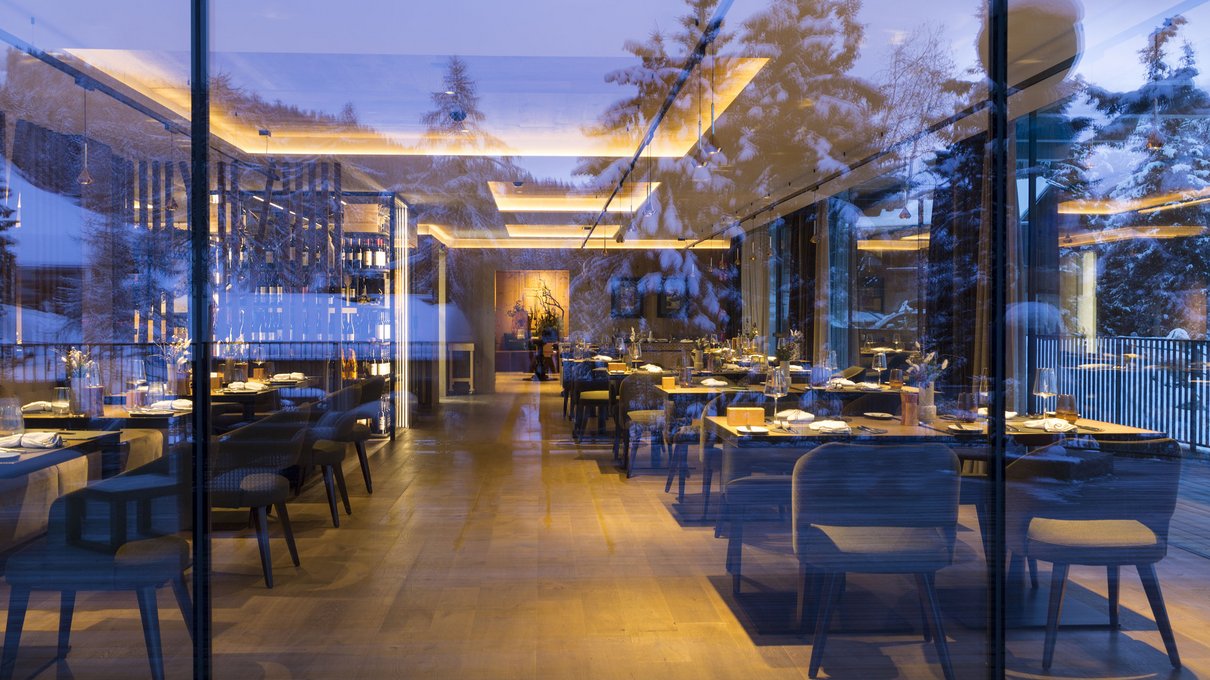 Deine Unterkunft im Pustertal: oh, wow! Innenansicht eines eleganten Restaurants mit verschneiten Bäumen im Fensterspiegel