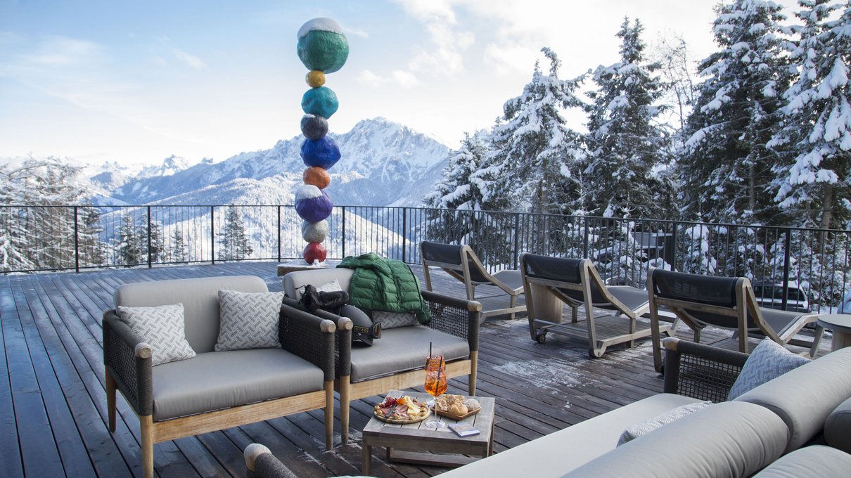 Deine Unterkunft im Pustertal: oh, wow! Terrasse mit Sofas, Snacks und farbiger Skulptur in verschneiter Berglandschaft