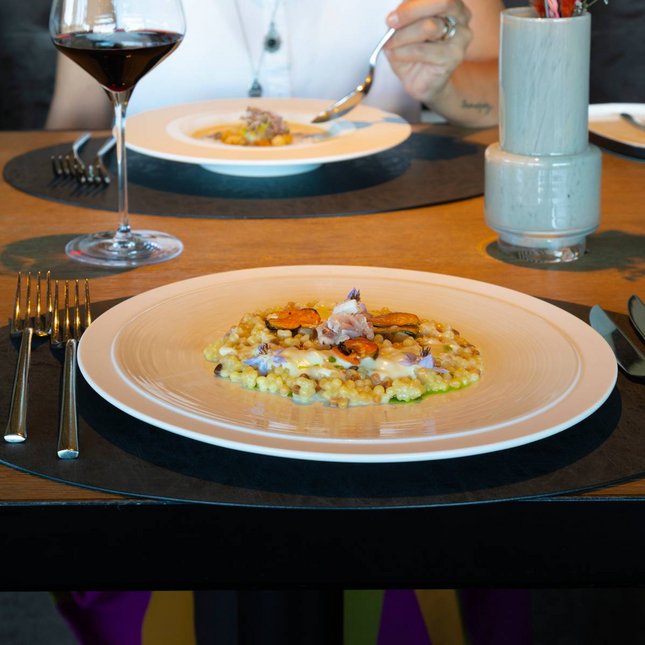 Hotel near Plan de Corones/Kronplatz: more flavour! Woman sitting at table with gourmet dishes and glass of red wine