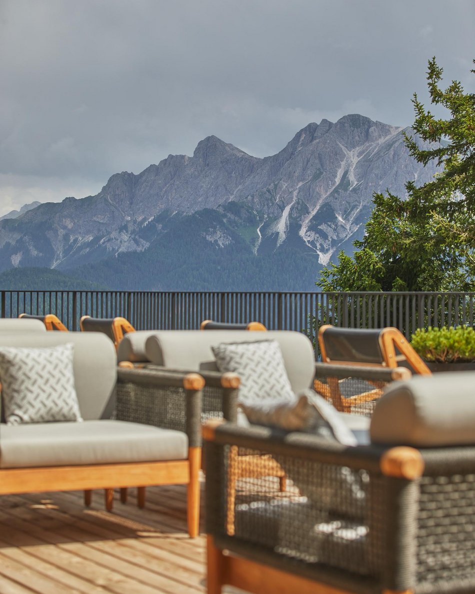 Il tuo hotel in Val Pusteria: Olangerhof Terrazza con divani e vista sulle montagne rocciose sotto un cielo nuvoloso
