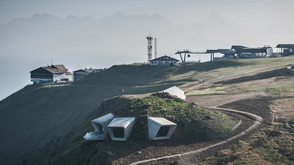 Olang: Wandern, Kunst und Kultur Moderne Gebäude auf einem Hügel mit nebligen Bergen im Hintergrund