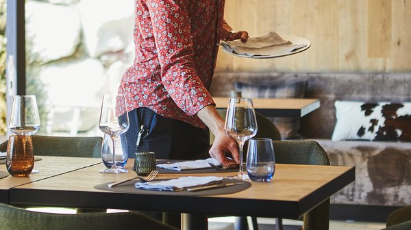 Hotels an der Piste in Südtirol mit Halbpension Kellner stellt Tische in einem stilvollen Restaurant ein