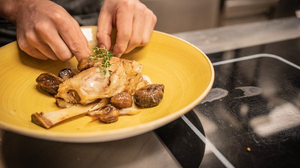 A Valdaora: l’hotel da “oh” Chef che guarnisce carne con erbe in piatto giallo