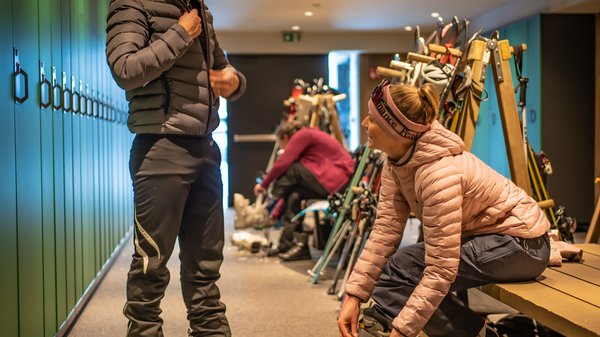 Kronplatz + Hotel an der Piste = Olangerhof Zwei Personen bereiten sich in einem Raum mit grünen Schließfächern auf das Skifahren vor