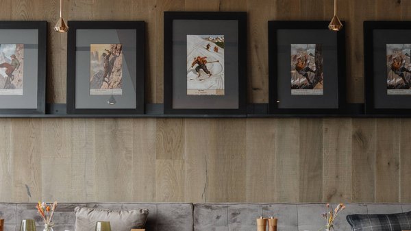 Hotels an der Piste in Südtirol mit Halbpension Innenraum eines Restaurants mit grauem Sofa, grünen Stühlen und gerahmten Bildern