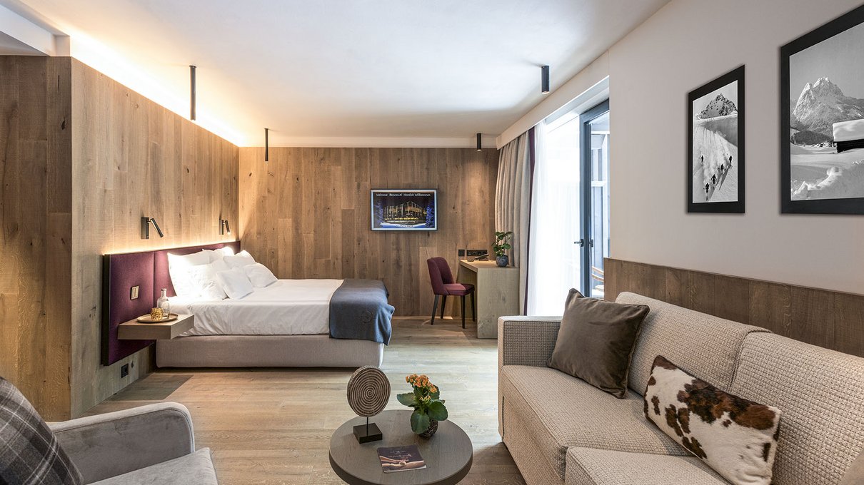 Deine Unterkunft im Pustertal: oh, wow! Modernes Hotelzimmer mit Bett, Sofa und Holzvertäfelung