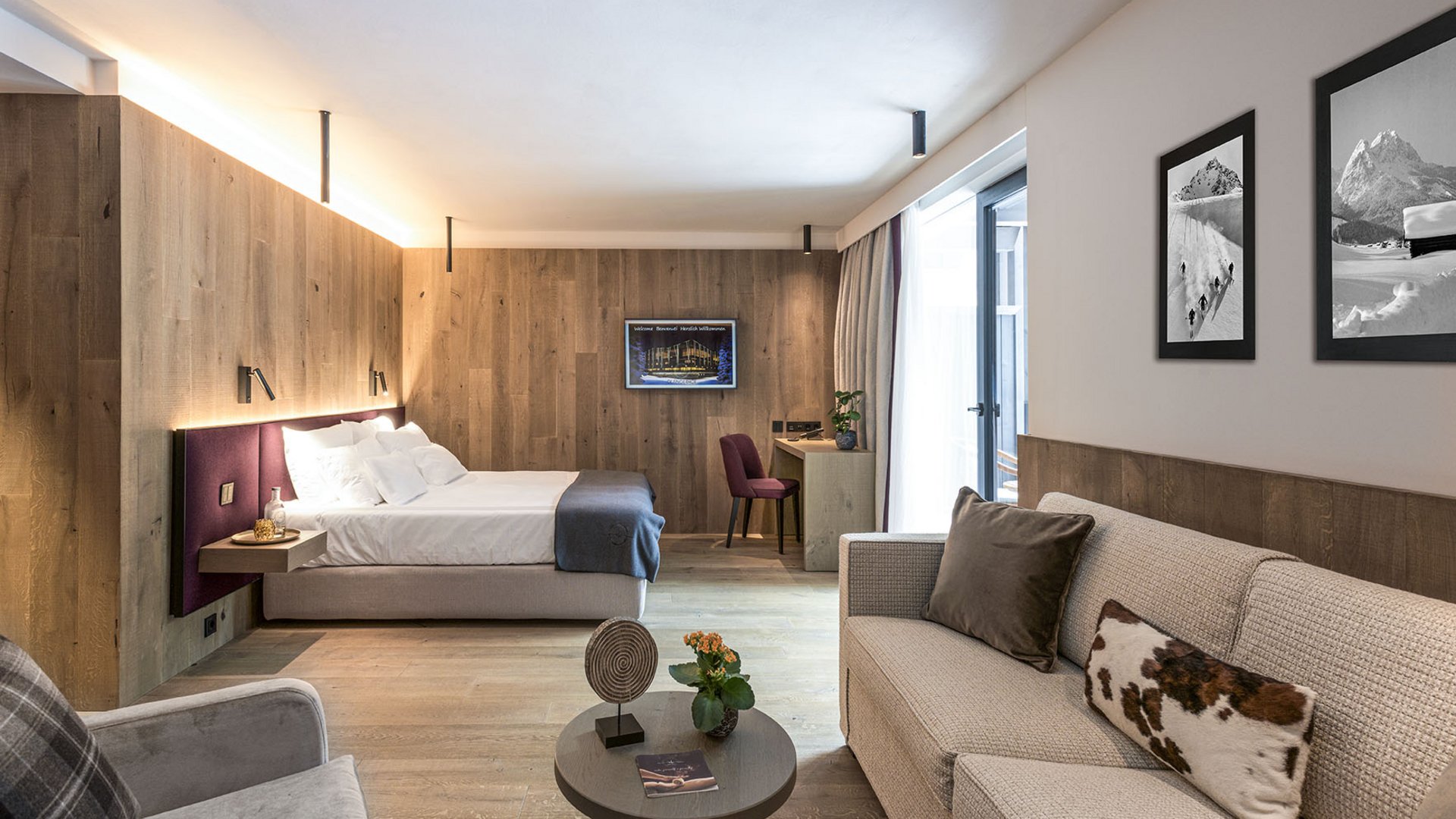 Your hotel in Val Pusteria/Pustertal with half board: oh, comfy Modern hotel room with bed, sofa, and wooden wall paneling