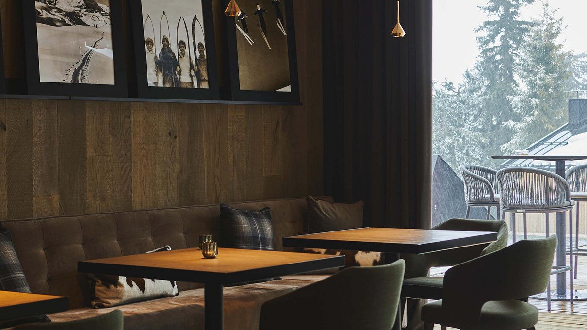 Deine Unterkunft im Pustertal: oh, wow! Gemütliches Barinterieur mit Holztischen und Fenstern mit Baumansicht