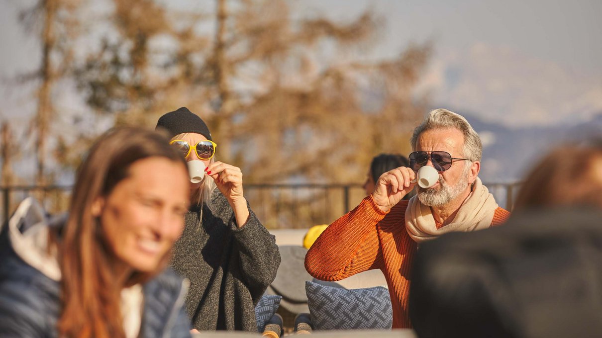 Deine Unterkunft im Pustertal: oh, wow! Ältere Menschen trinken an einem sonnigen Tag draußen Kaffee