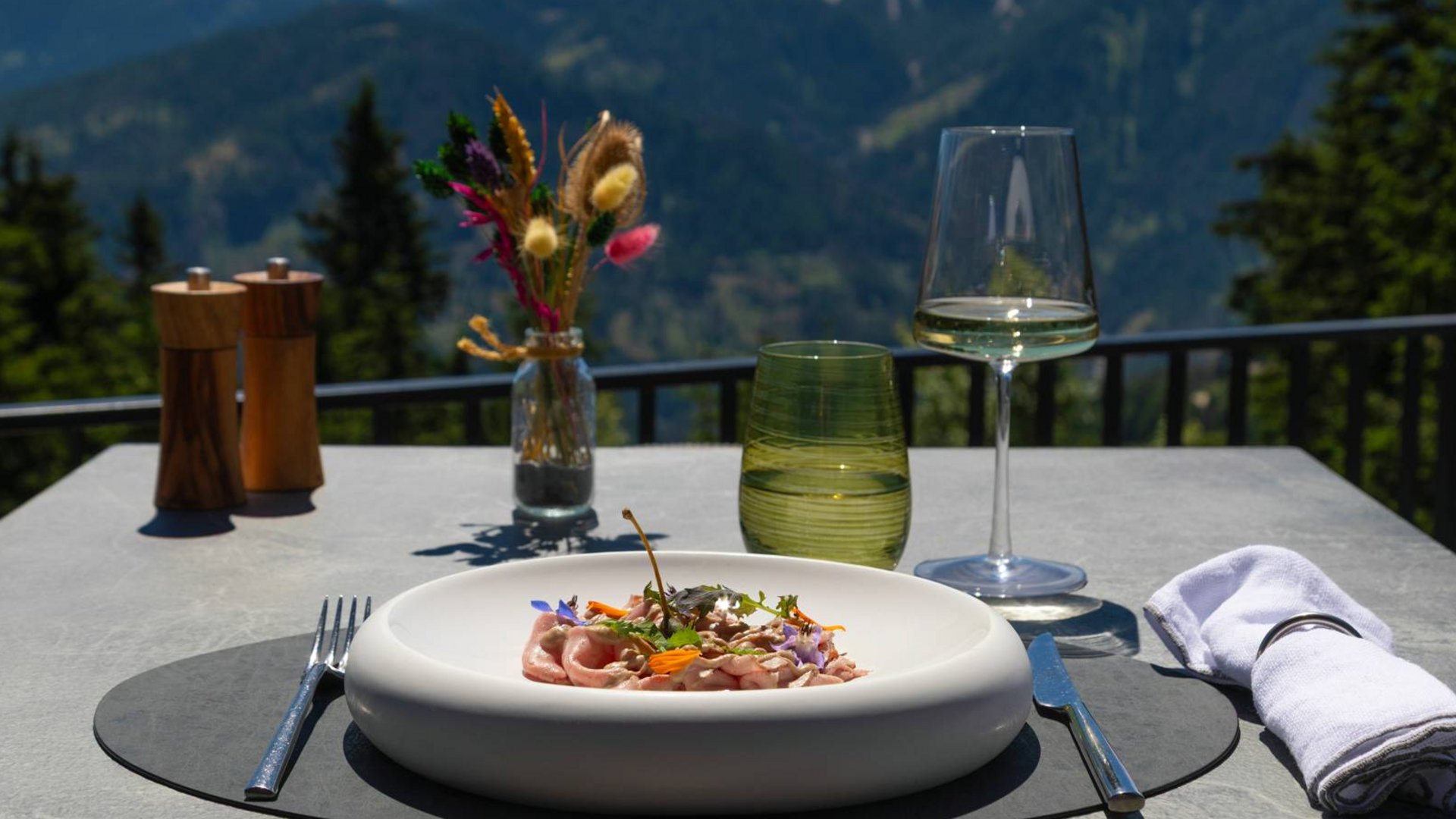 Hotel near Plan de Corones/Kronplatz: more flavour! Gourmet dish with wine glass on outdoor table overlooking mountains