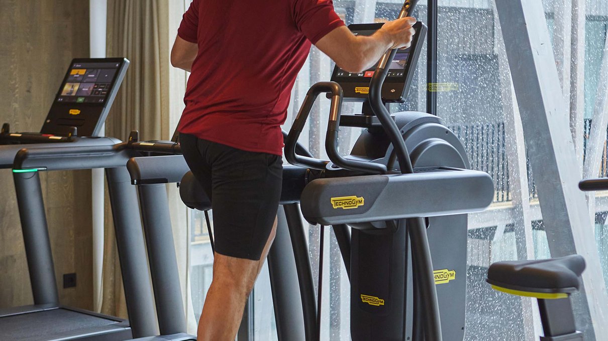 Deine Unterkunft im Pustertal: oh, wow! Mann trainiert auf Ellipsentrainer in modernem Fitnessstudio mit Glaswand