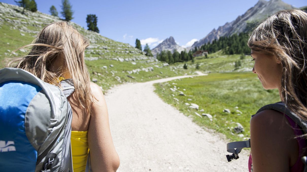 Deine Unterkunft im Pustertal: oh, wow! Zwei Frauen mit Rucksäcken wandern auf einem sonnigen Bergweg
