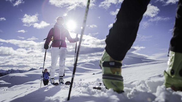 Kronplatz + Hotel an der Piste = Olangerhof Menschen wandern mit Schneeschuhen an einem sonnigen Wintertag in den Bergen