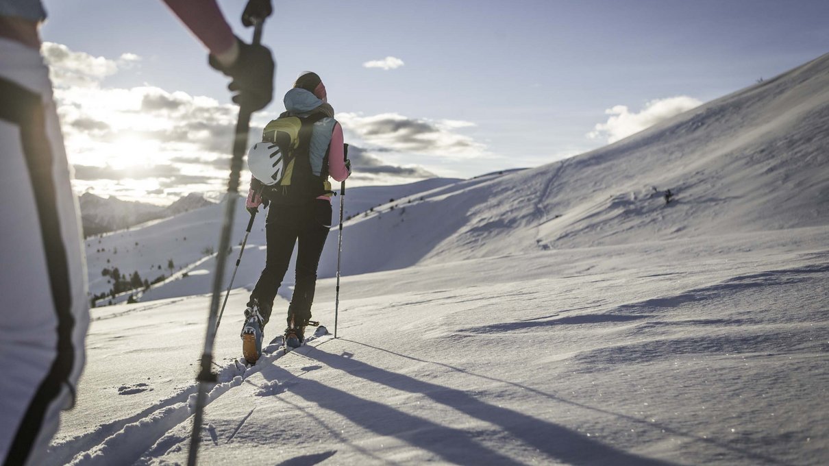 Deine Unterkunft im Pustertal: oh, wow! Menschen beim Aufstieg mit Skiern auf verschneitem Berg bei Sonnenuntergang