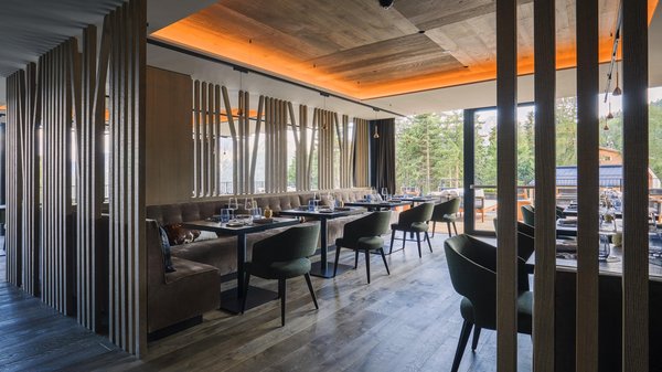 Hotels an der Piste in Südtirol mit Halbpension Innenraum eines modernen Restaurants mit grünen Stühlen und Holzdekor