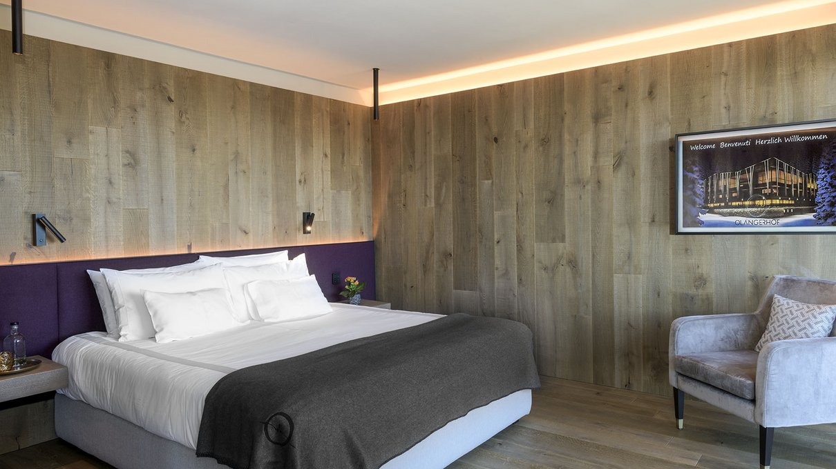 Deine Unterkunft im Pustertal: oh, wow! Modernes Schlafzimmer mit Holzwänden, Doppelbett und grauem Sessel