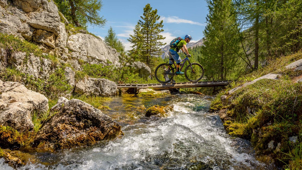Deine Unterkunft im Pustertal: oh, wow! Radfahrer mit Helm überquert Holzbücke über Bergbach