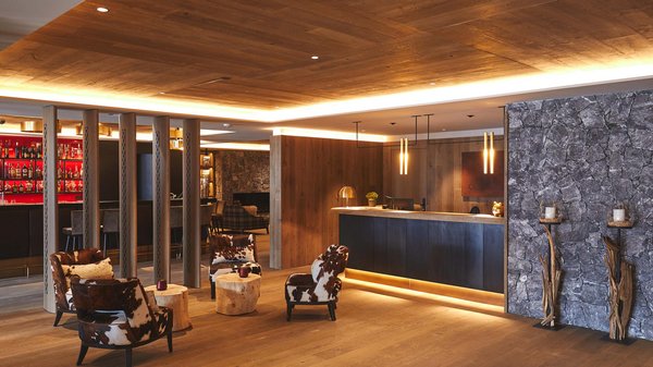 Dein Hotel in Olang: Willkommen im Olangerhof! Hotelrezeption mit Kuhfellstühlen und Holzmöbeln.