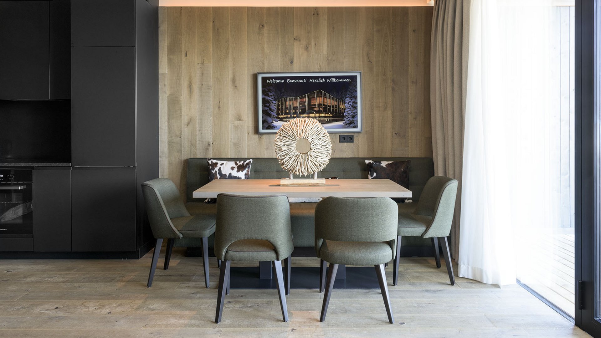 Hotels im Pustertal mit Halbpension: oh, so comfy! Moderner Wohnraum mit Tisch, grünen Stühlen und großem Fenster mit Vorhängen