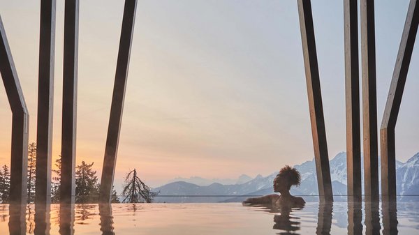Dein Wellnesshotel am Kronplatz: Olangerhof Frau im beheizten Pool mit Bergblick bei Sonnenuntergang