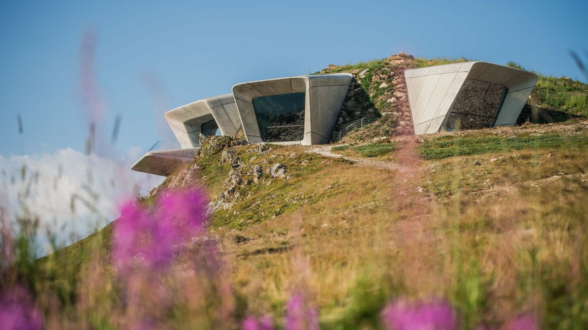Deine Unterkunft im Pustertal: oh, wow! Modernes Gebäude mit großen Fenstern auf einem blühenden Hügel bei blauem Himmel