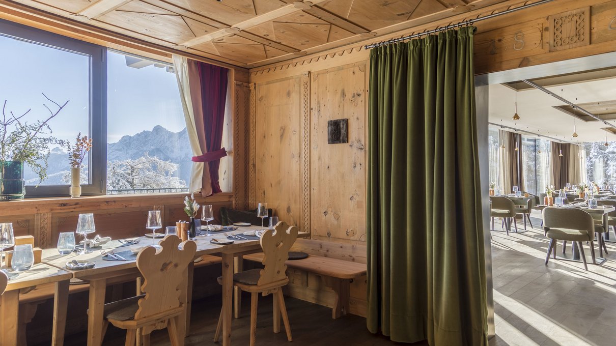 Deine Unterkunft im Pustertal: oh, wow! Holzrestaurant mit Blick auf schneebedeckte Berge durch ein Fenster