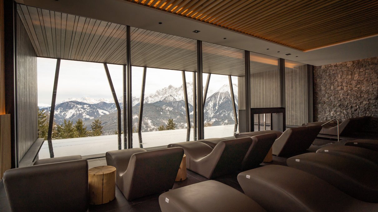 Il tuo alloggio in Val Pusteria: rifatti gli occhi! Salotto moderno con grandi finestre che mostrano montagne innevate