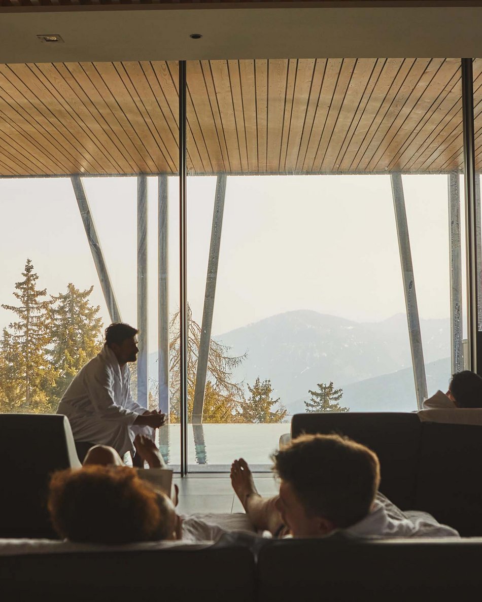 Hotel in Plan de Corones/Kronplatz with pool: Olangerhof People in robes relaxing on sofas with mountain view through large glass windows