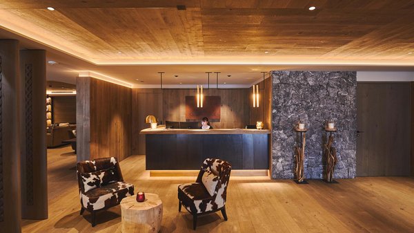 A Valdaora: l’hotel da “oh” Reception accogliente con arredi in legno e due poltrone con tavolino tronco